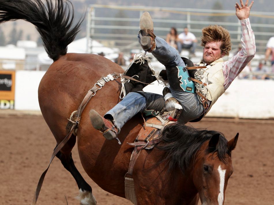 A man flies sideways off a bucking horse during the 2015 Klickitat County Fair Rodeo.