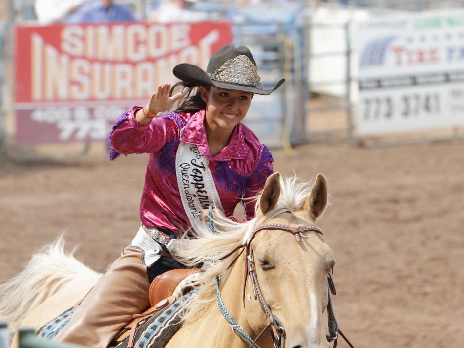 The 2015 Toppenish Rodeo Queen waves to the crowd as she rides by on her horse.