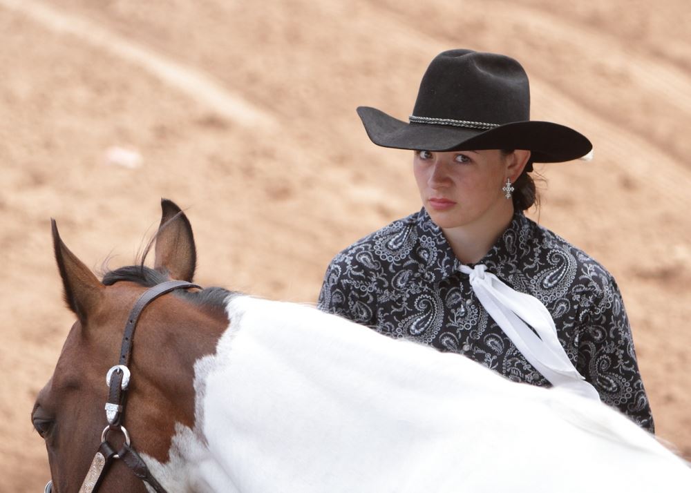 A young woman stands next to her horse in the arena at the 2014 Klickitat County Fair.