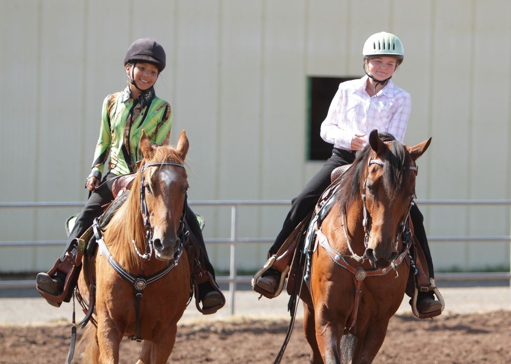 Two girls ride their horses in the arena at the 2014 Klickitat County Fair.