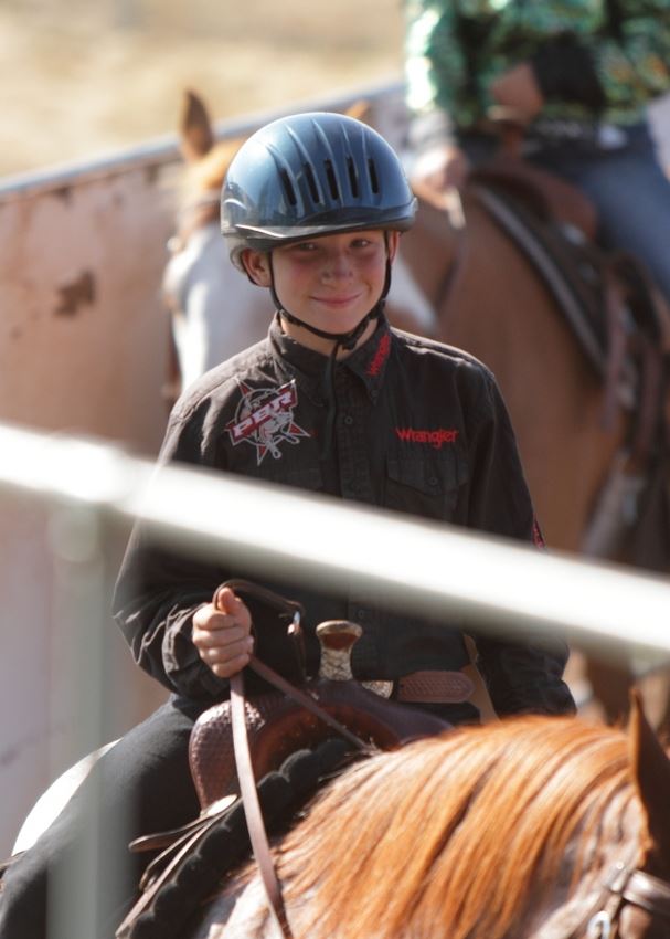 A  young man smiles as he rides his horse in the arena at the 2014 Klickitat County Fair.