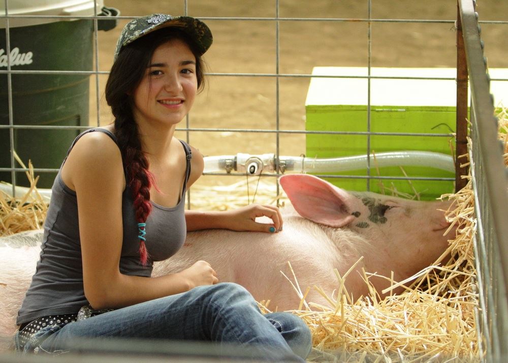 A girl sits next to her sleeping pig at the 2014 Klickitat County Fair.
