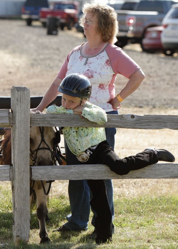 A little girl rests against a wooden fence at the 2014 Klickitat County Fair.