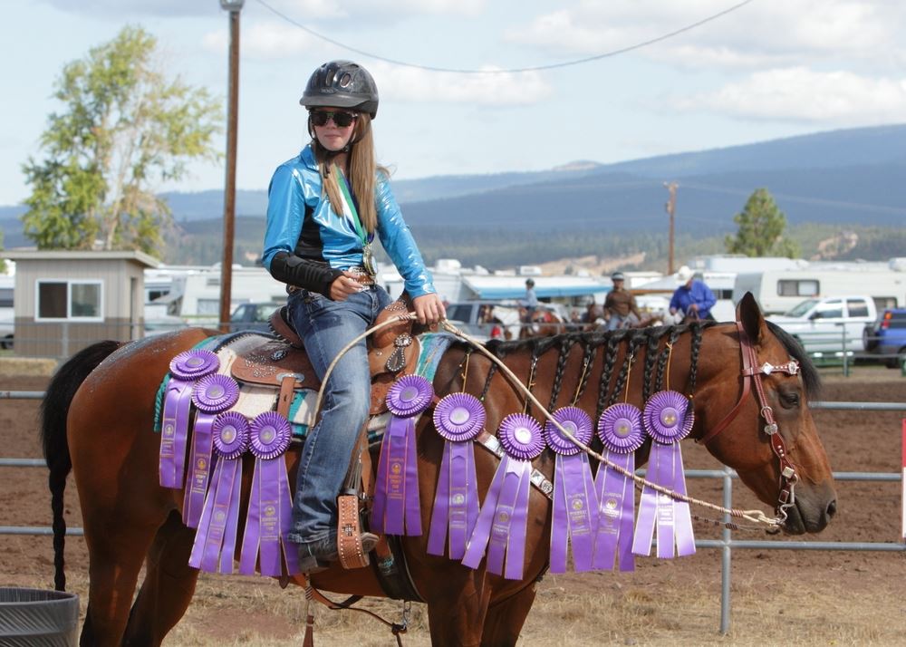 A girl sits atop her awarded ribbon adorned horse at the 2014 Klickitat County Fair.