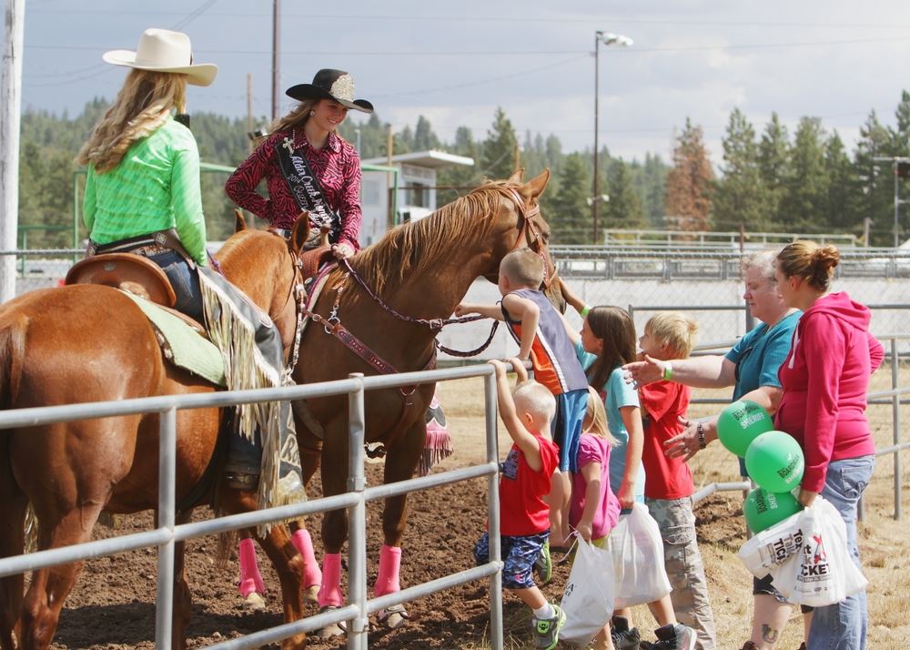 A group of children pet the horse of the Rodeo Queen.