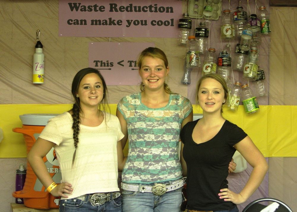 Three girls pose at the Waste Reduction exhibit.