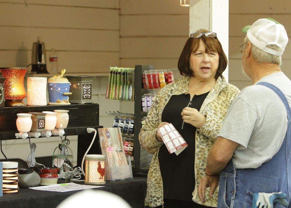 A woman talks to a man at the Scentsy exhibit at the 2014 Klickitat County Fair.
