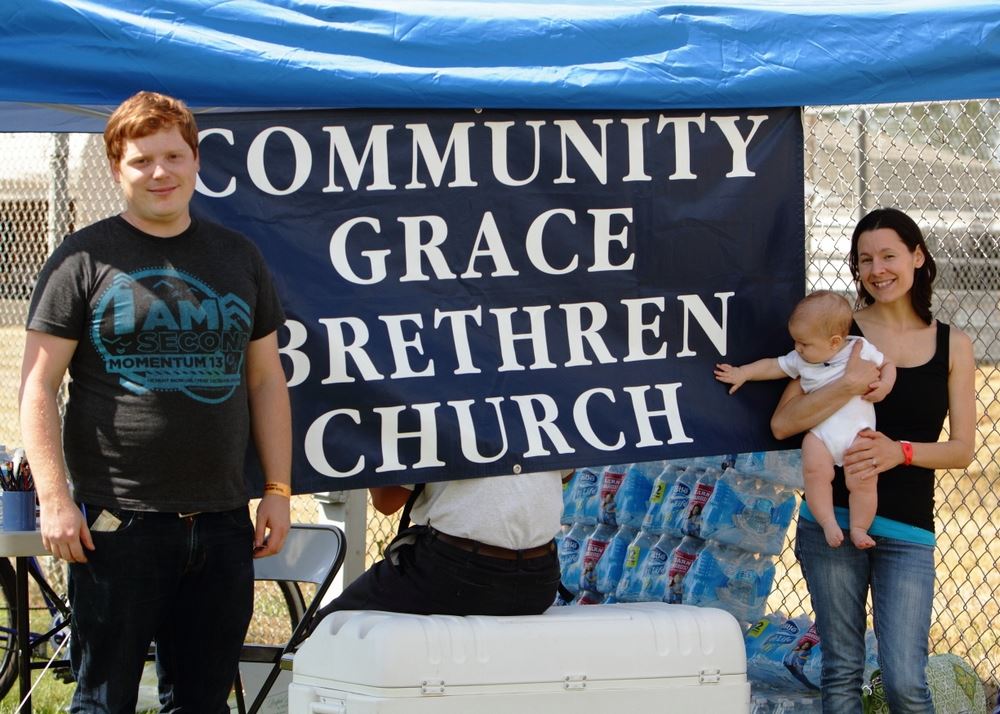 A man and a woman holding a baby stand at the Community Grace Brethren Church exhibit.