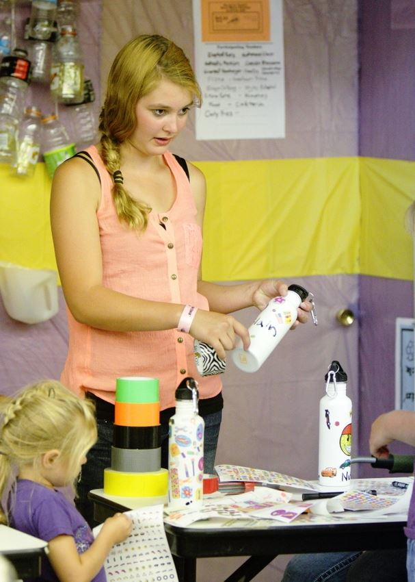 A girl stands behind the desk at the Waste Reduction exhibit.