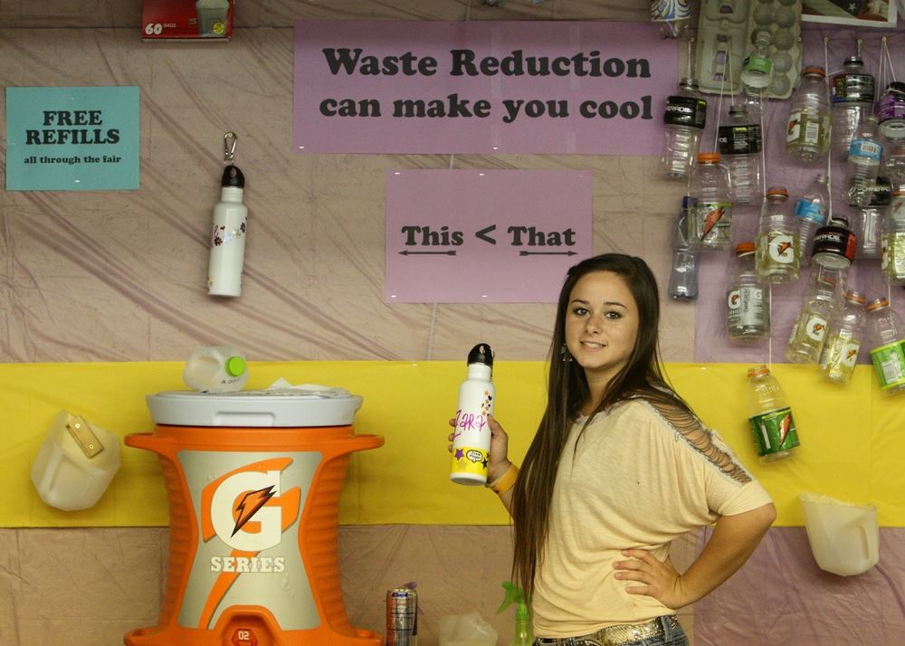 A girl holds her reusable water bottle at the Waste Reduction exhibit.