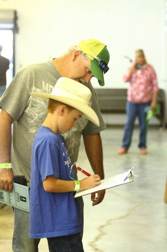 A little boy signs a piece of paper at the 2014 Klickitat County Fair.