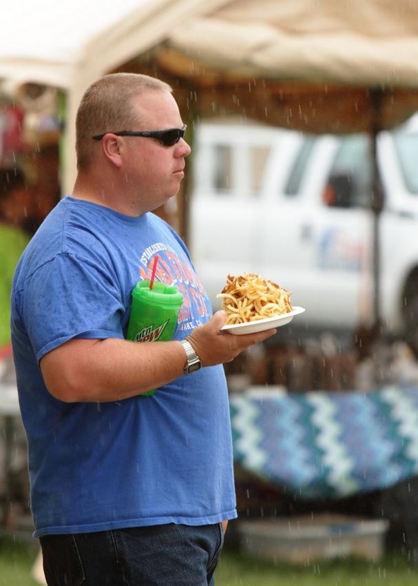 A man holds a plate of curly fries at the 2014 Klickitat County Fair.