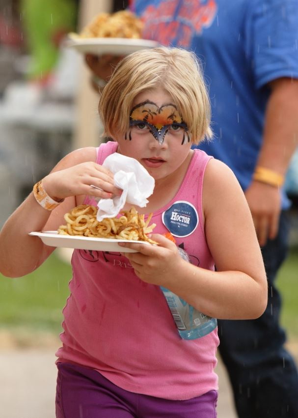 A little girl eats some curly fries at the 2014 Klickitat County Fair.