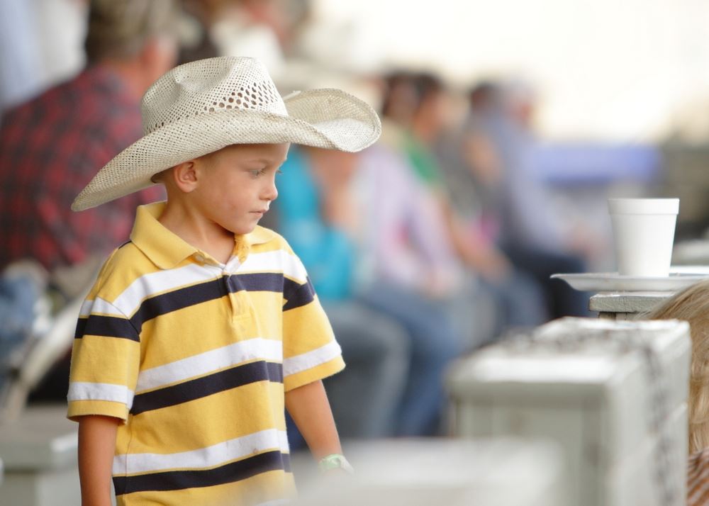 A little boy in a cowboy hat stands in front of the crowd at the 2014 Klickitat County Fair.