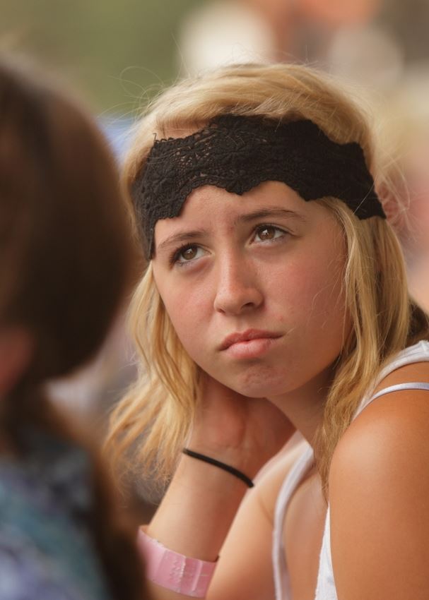 A girl with a black head band on sits among the crowd at the 2014 Klickitat County Fair.
