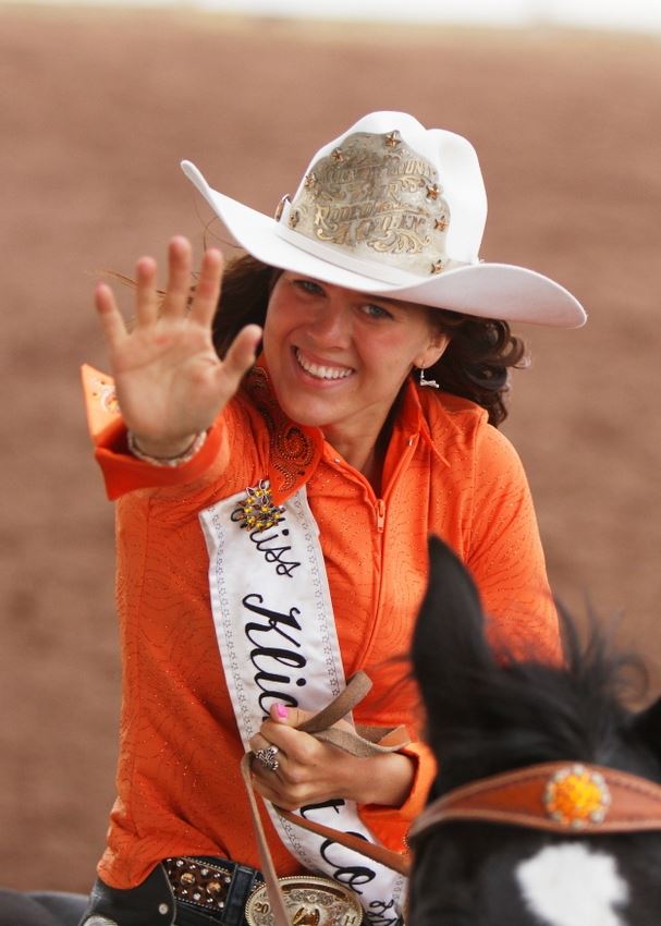 The Klickitat County Fair and Rodeo Queen waves to the crowd while riding by on her horse.