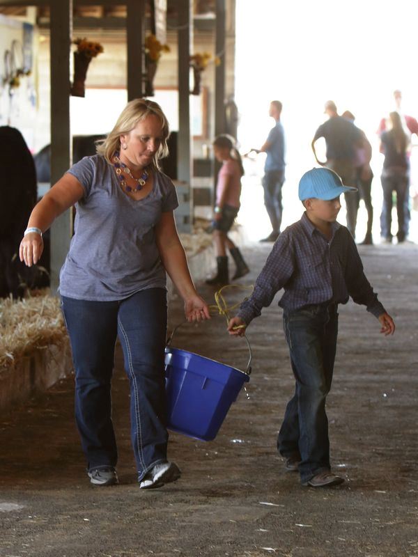 Woman and little boy carry a blue bucket together.