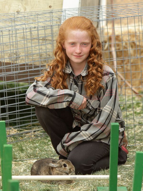 A girl kneels down next to her rabbit at the 2015 Klickitat County Fair.