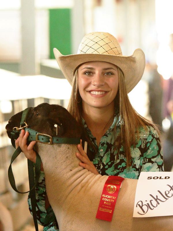 A girl smiles holding the head of her show sheep.