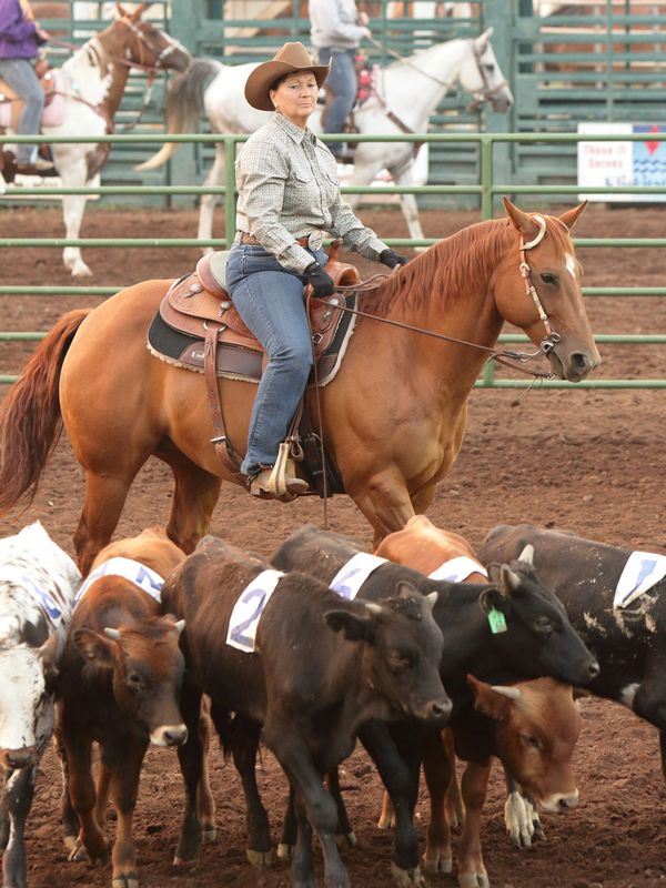 A woman herds calves on her horse at the 2015 Klickitat County Fair.