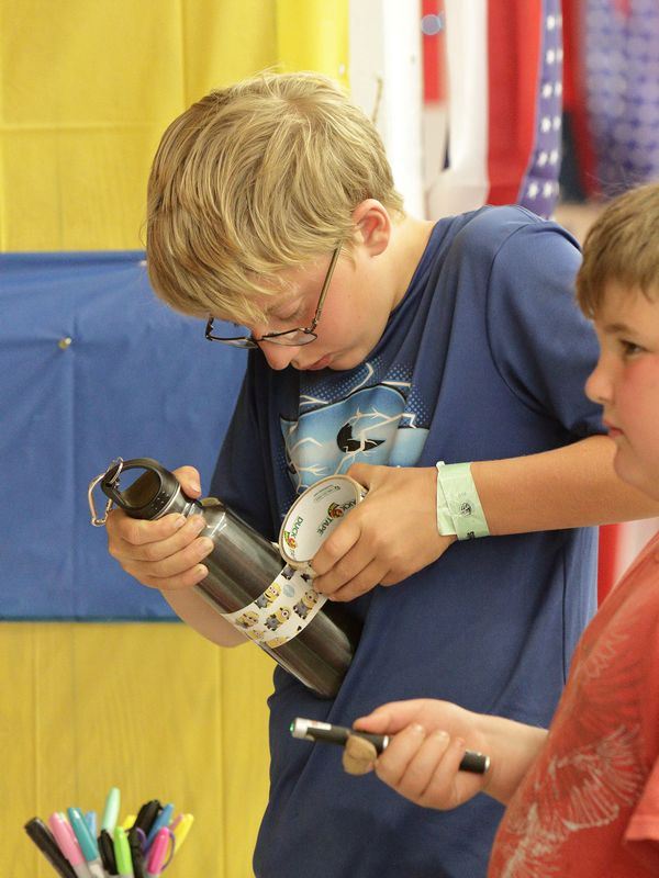 A boy decorates his reusable water bottle with Minion duct tape.