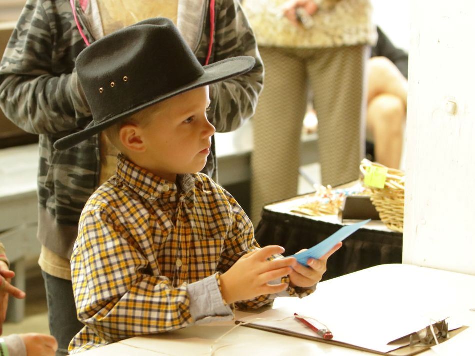 Little boy listens intently at a booth for the 2015 Klickitat County Fair.