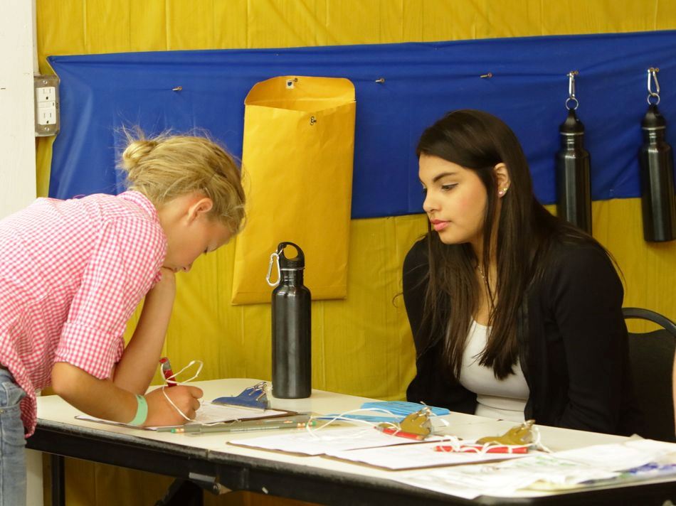 Girl writes on a piece of paper at the Waste Reduction exhibit.