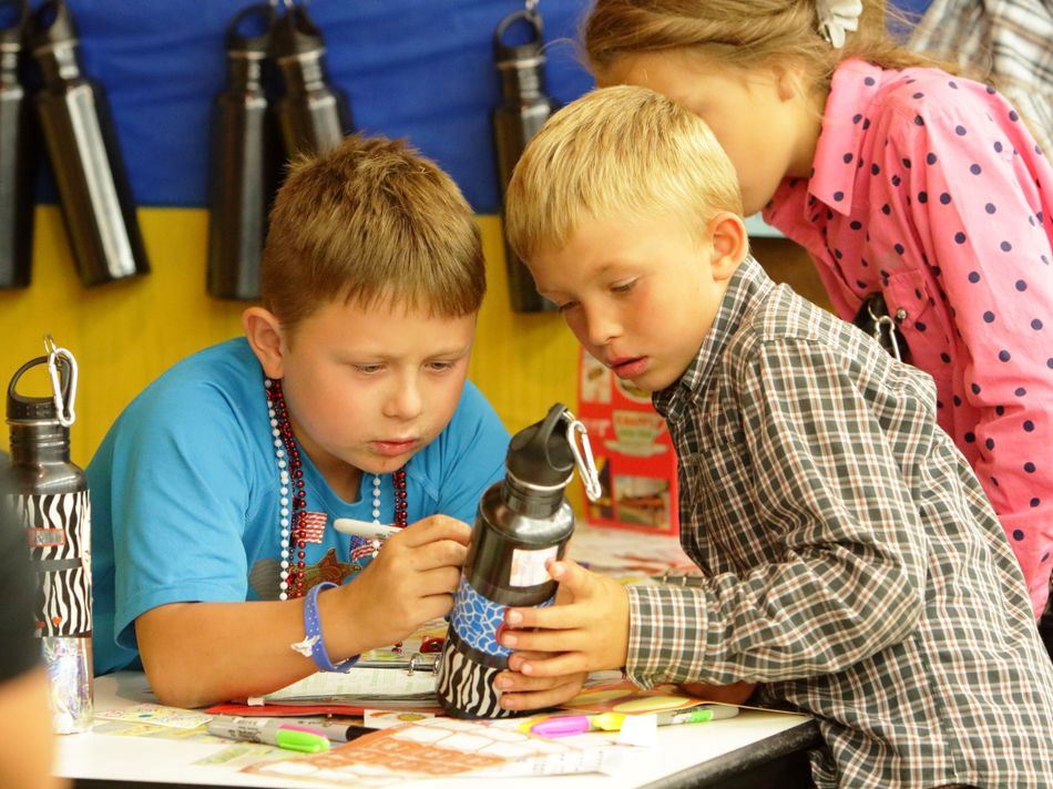 Little boys decorate their reusable water bottles.