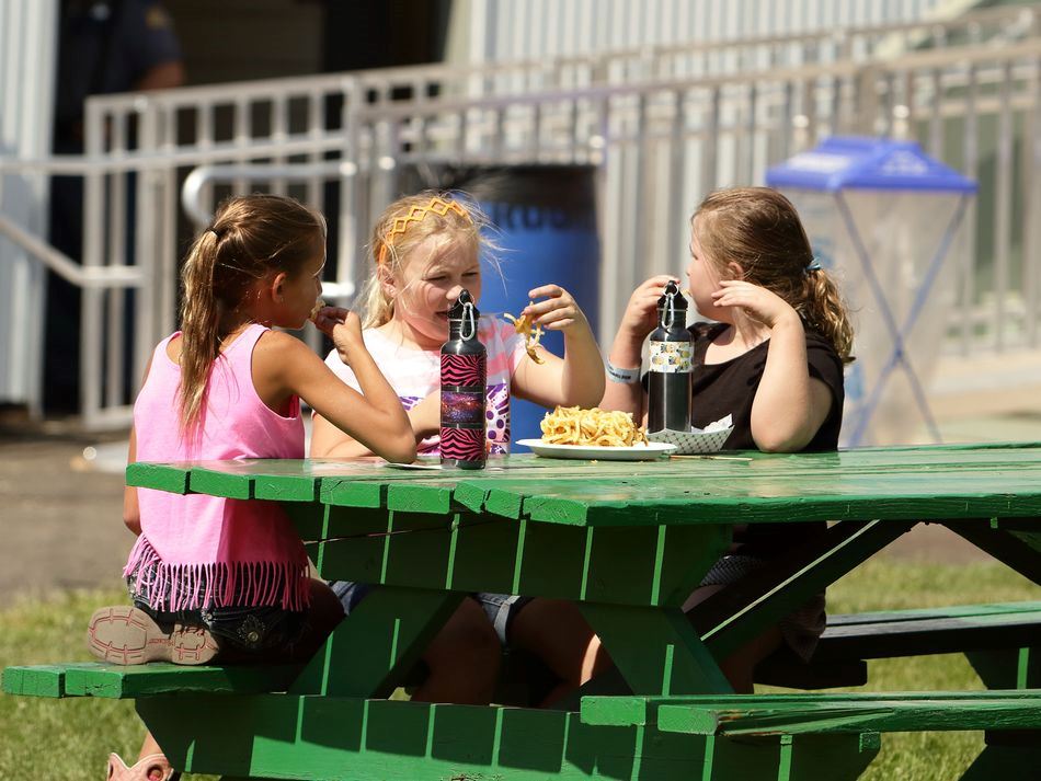 A group of girls sit together at a picnic table at the 2015 Klickitat County Fair.
