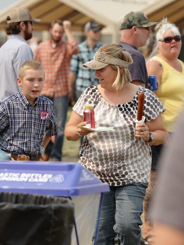 A woman holds a corn dog and a Dr. Pepper while chatting with a boy at the 2015 Klickitat County Fair.