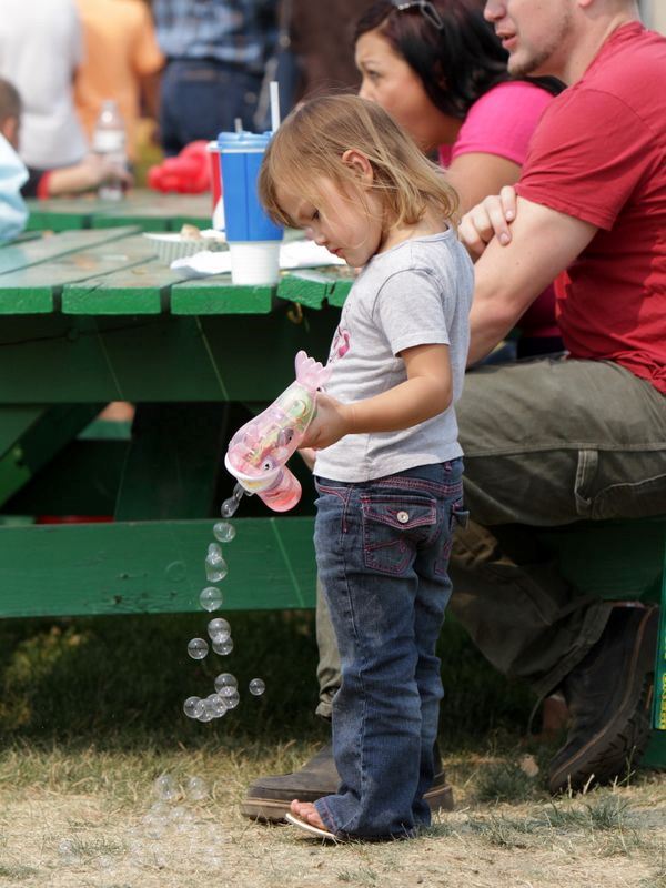 A little girl plays with a bubble gun at the 2015 Klickitat County Fair.