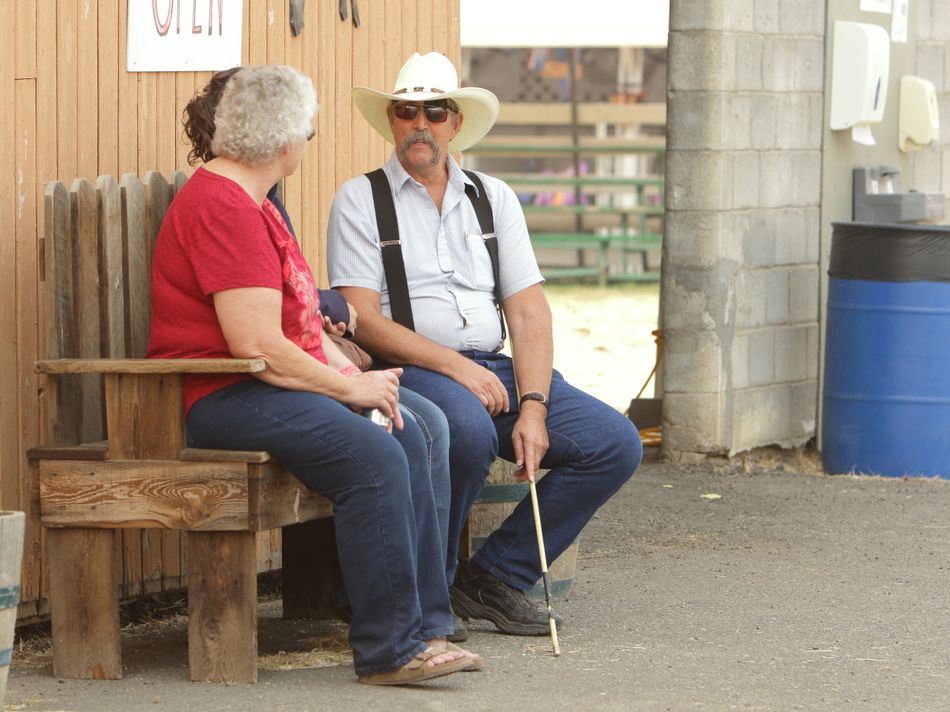 Three people sit on a bench together chatting.