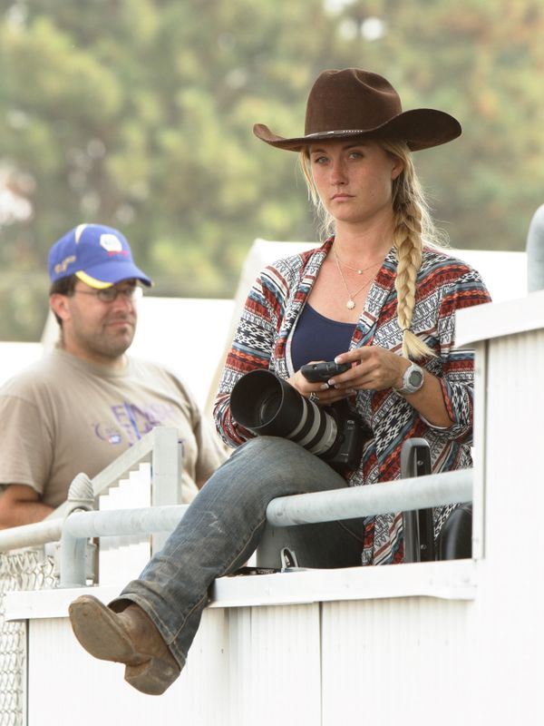 A woman checks her cellphone and holds a large camera in her lap at the 2015 Klickitat County Fair.